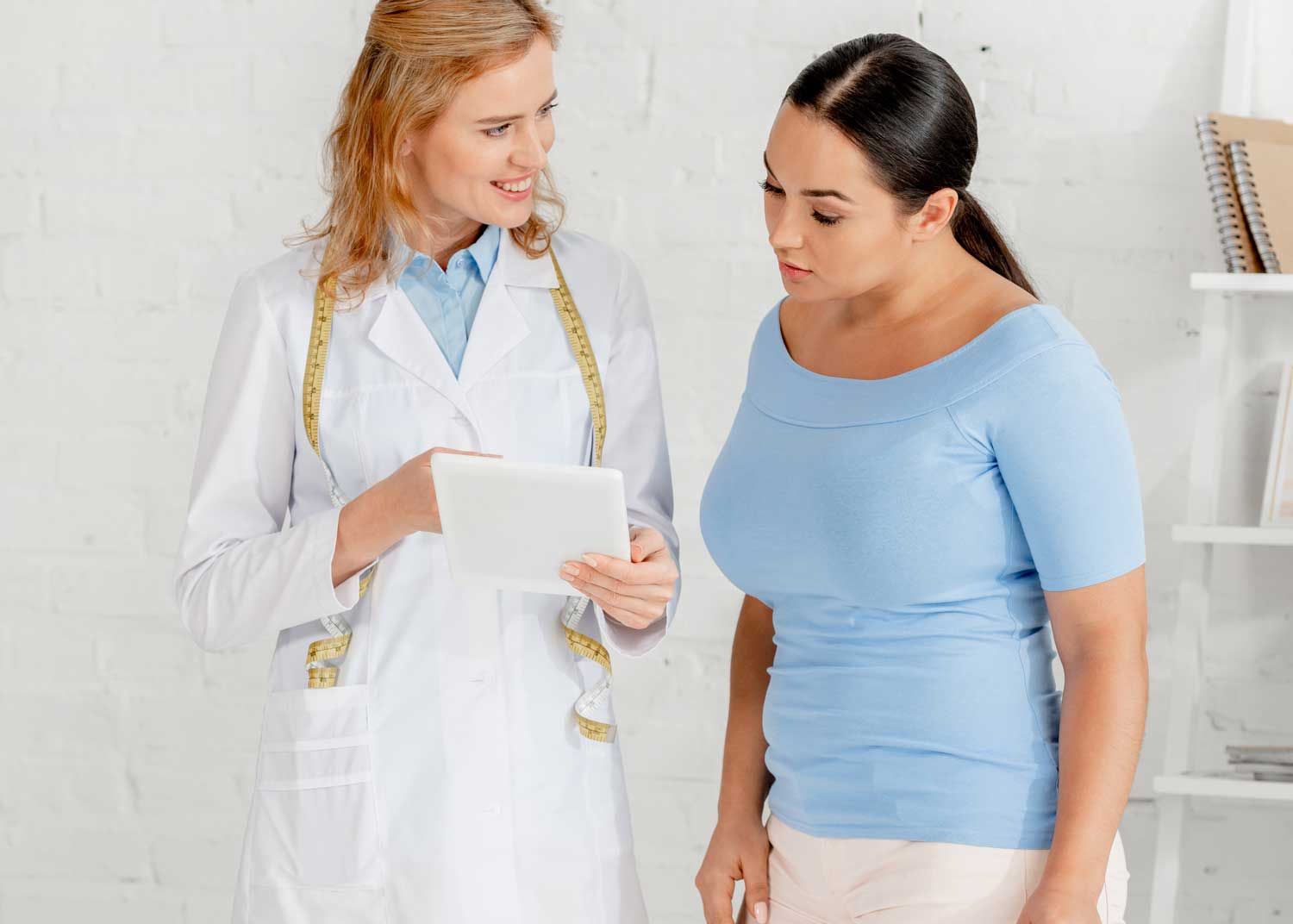 A woman sits on an exam table and talks to a nurse