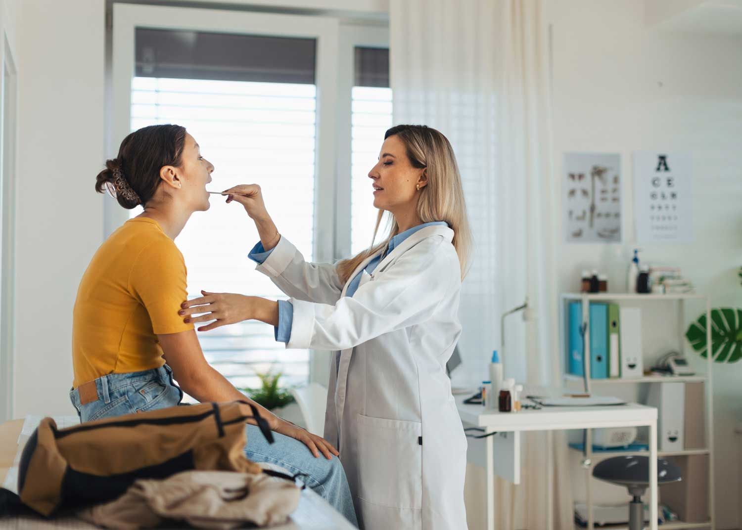 A woman sits on an exam table and talks to a nurse