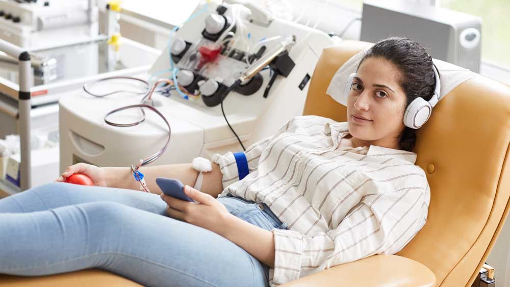 A woman sits on an exam table and talks to a nurse